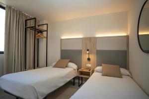 two beds in a hotel room with a mirror at Dynastic Rooms Apartments in Benidorm +15 photos