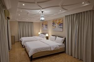 a bedroom with two beds and a chandelier at Mountain Majesty 4 Bed Home - BBQ Retreat in Masāfī