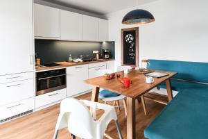 a kitchen with a wooden table and a blue couch at Apartment mit überdachter Terrasse 7 7 EG in Friedrichshafen