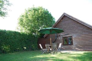 a table and chairs with an umbrella in front of a house at The Chalet is pet friendly on a farm near Malvern in Welland