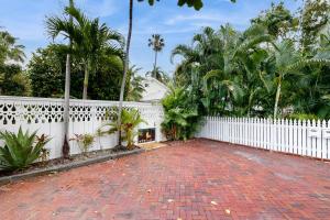 une clôture blanche et une allée en briques avec des palmiers dans l'établissement Last Minute, à Key West