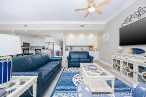 a living room with a blue couch and a kitchen at Phoenix Orange Beach II 603 condo in Orange Beach