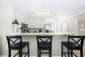 a white kitchen with two black chairs at a counter at Phoenix Orange Beach II 603 condo in Orange Beach