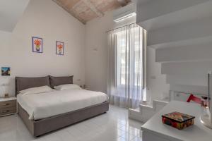 a white bedroom with a bed and a window at Mansarda del Corso in Sorrento