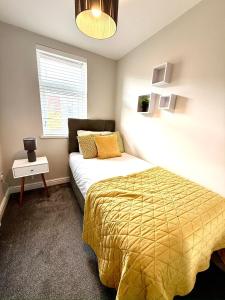 a bedroom with a bed with a yellow comforter and a window at Luxurious Modern House With Garden Close To City Centre in Cardiff