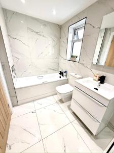 a white bathroom with a tub and a toilet and a sink at Luxurious Modern House With Garden Close To City Centre in Cardiff +26 photos