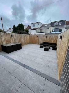 a patio with benches and a wooden fence at Luxurious Modern House With Garden Close To City Centre in Cardiff