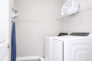 a white laundry room with a washer and dryer at Home With Splash Pad And Slide, Movie Theater & Game Room With Waterpark & Resort Access - 417Sf in Kissimmee