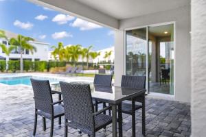 a patio with a table and chairs next to a pool at Home With Splash Pad And Slide, Movie Theater & Game Room With Waterpark & Resort Access - 417Sf in Kissimmee