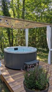 a hot tub on a wooden deck with a pergola at Lodge Hérisson avec Spa privatif in Biron +1 photo
