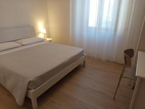 une chambre blanche avec un lit et une fenêtre dans l'établissement LorMar House, à Oristano