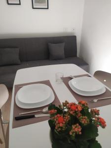 une table avec deux plaques blanches et une plante sur elle dans l'établissement LorMar House, à Oristano