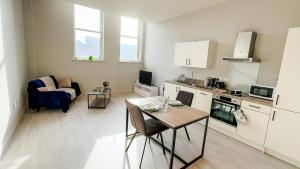 a living room with a table and a kitchen at Prime Leeds- Spacious Cinema apartment in Central Station
