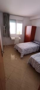 a bedroom with two beds and a desk and a window at Marcotin Piscina playa y montaña in Alcossebre