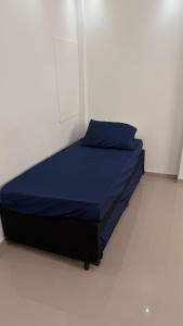 een bed in een witte kamer met een blauwe deken bij Apê da divisa in São Vicente +8 foto's