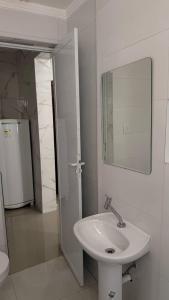 een witte badkamer met een wastafel en een spiegel bij Apê da divisa in São Vicente