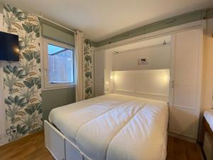 a bedroom with a white bed with a window at My 3 stars BEE HAPPY studio in Brides-les-Bains