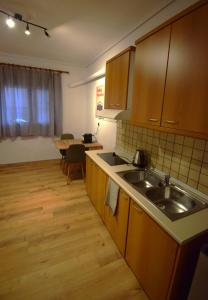 une cuisine avec des armoires en bois, un évier et une table dans l'établissement Balkanisateur Studio C, à Kavala
