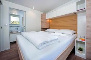 ein Schlafzimmer mit einem großen weißen Bett mit einem hölzernen Kopfteil in der Unterkunft Eurocamp Mobile Homes at Campsite Puntica in Funtana