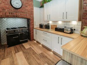 a kitchen with white cabinets and a brick wall at Sunflowers in Whitley Bay