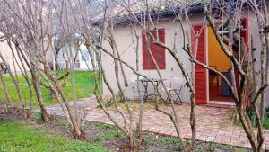 a small white house with red shutters and trees at La Fetuseria bistrot & camere in Senigallia
