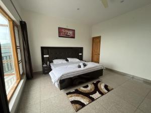 a bedroom with a bed and a large window at The village lodge Dalhousie in Banikhet