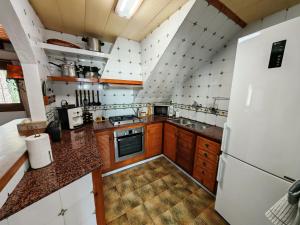 a kitchen with wooden cabinets and a white refrigerator at Ca la Consol in El Poblenou del Delta