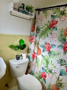 a bathroom with a toilet with a tropical shower curtain at Tranquil home with pool near ocean in Jensen Beach