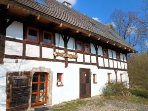 a white building with a wooden roof at Smocza Chata in Mirsk