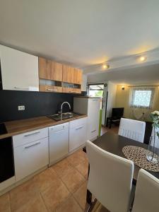 a kitchen with white cabinets and a table with chairs at Apartment Kaucic in Banjole +5 photos