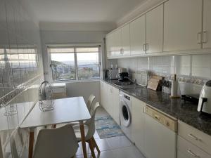 a kitchen with white cabinets and a table with chairs at Ancoravilla in Vila Praia de Âncora