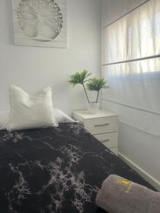 a bedroom with a bed and a nightstand with two plants at LM apartamentos Alfacar in Alfacar