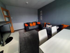 ein Wohnzimmer mit 2 Sofas und orangefarbenen Kissen in der Unterkunft 2 Bedroom, free parking & Netflix near hospitals in Aberdeen