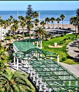 a view of a park with palm trees and the beach at Apprt Ennakhil 2 in El Jadida