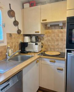 a small kitchen with a sink and a microwave at Maison Opaline in Le Touquet-Paris-Plage