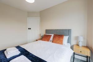 Un dormitorio con una gran cama blanca con almohadas naranjas. en The Broadway, en Warrenby