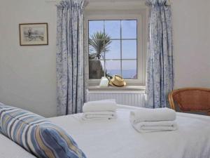 a bedroom with a bed with a window and towels at Watchtower in Torpoint