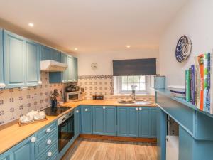 a kitchen with blue cabinets and a sink at Watchtower in Torpoint