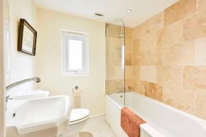 a bathroom with a toilet and a tub and a sink at GuestReady - Charming family retreat in London in London