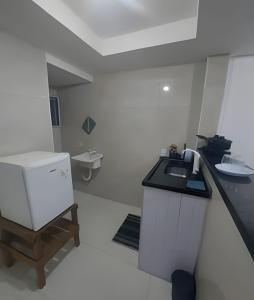 La cuisine blanche est équipée d'un évier et d'un réfrigérateur. dans l'établissement lindo apartamento recreio dos bandeirantes, à Rio de Janeiro