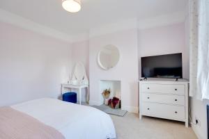 ein weißes Schlafzimmer mit einem Bett und einem Fernseher in der Unterkunft NEW The Procession Grade II Listed and Pet Friendly in Berwick-Upon-Tweed