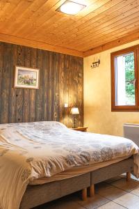 a bedroom with a large bed with wooden walls at La Grange des Mios in La Bresse