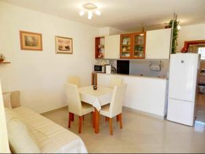 a kitchen with a table and chairs and a white refrigerator at Apartment Darko in Tribunj