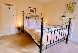 ein Schlafzimmer mit einem Bett und einem Tisch mit einer Lampe in der Unterkunft Deben Cottage, Central Woodbridge in Woodbridge