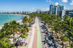 a city street with palm trees and a beach at Seu Refúgio a 100m da Praia do Sobral - Maceió in Maceió
