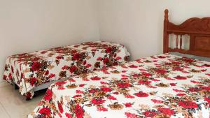 a bedroom with two beds with flowers on them at Chalé Confortável e Completo com piscina in Roças Novas +18 photos