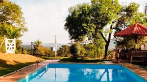 a swimming pool in a yard with a gazebo at Chalé Confortável e Completo com piscina in Roças Novas