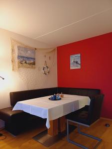 a table in a room with a red wall at Ferienwohnung Seelenbrise in Büsum +11 photos