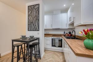 a kitchen with white cabinets and a black island with bar stools at Stylish 2 Bedroom Apartment in Belfast in Belfast +22 photos