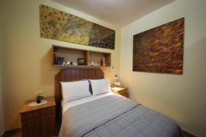 a bedroom with a bed and a painting on the wall at OKE Apart Hotel in San Lorenzo
